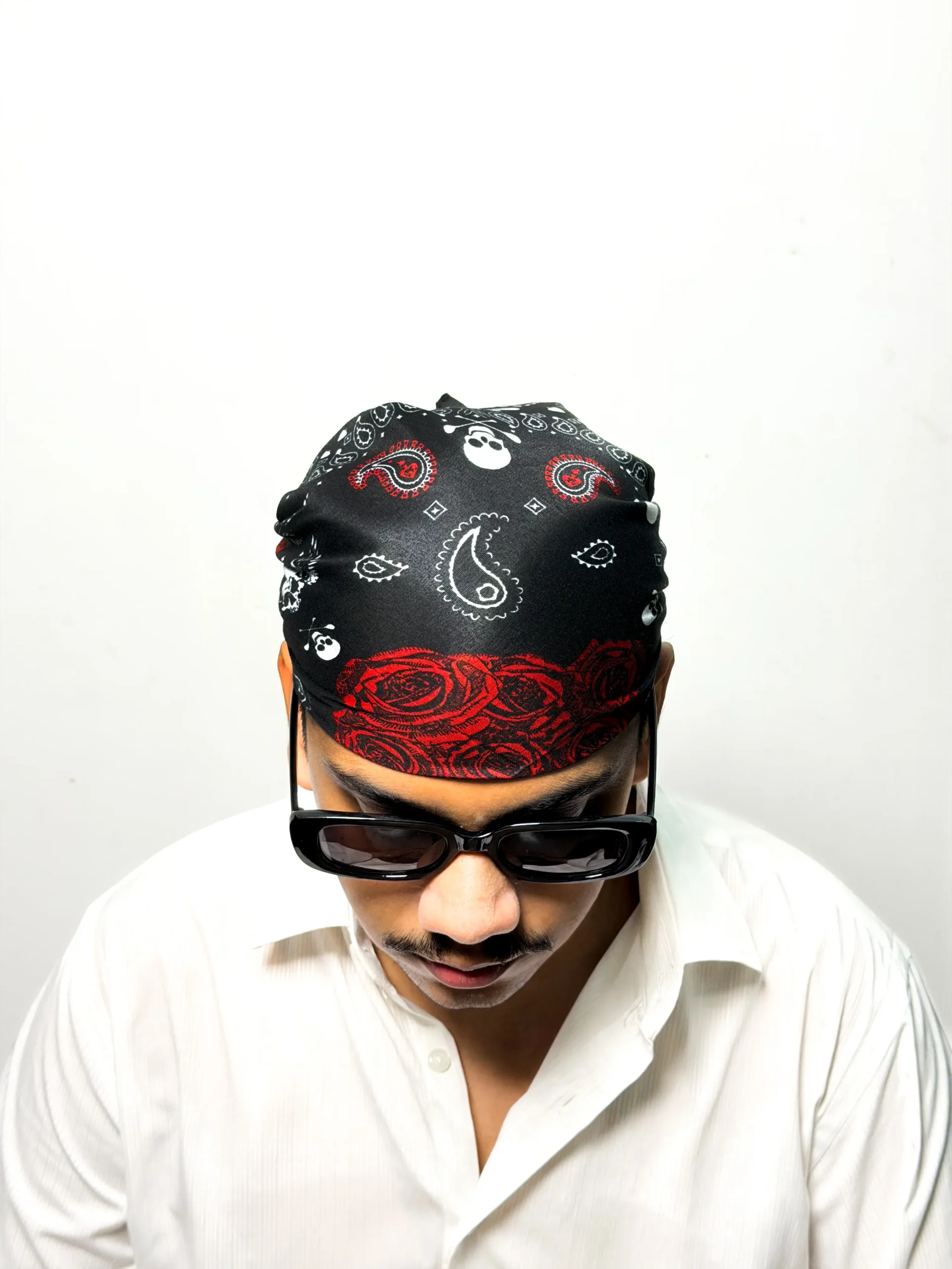 Black printed bandana with white paisley, skulls, and red rose design